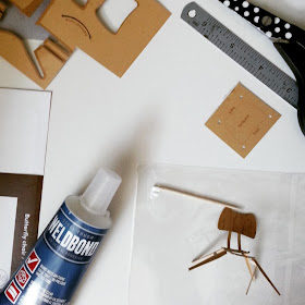 Glue, ruler, scissors and toothpick plus a half-built cardboard model of a 1958 Ercol butterfly chair.