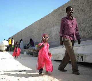 A little girl and her father walk on Lido beach in Mogadishu, Somalia, during Eid al-Fitr, the Muslim holiday marking the end of Ramadan.