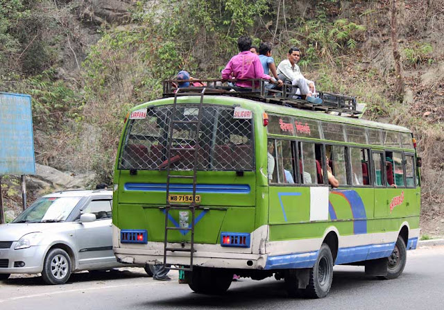 people sitting on the roof of a bus