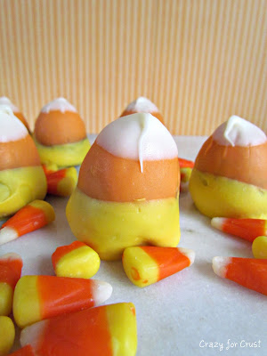 brownie bites dipped in chocolate to look like candy corn on marble slab with candy corn around