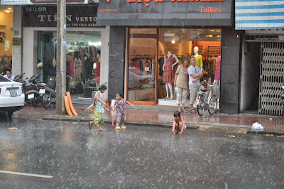 Niños jugando bajo la lluvia en Ciudad Ho Chi Minh