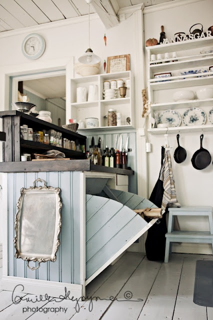 These cubby cabinets and whitewashed pallet floor are cozy elements of this farmhouse kitchen