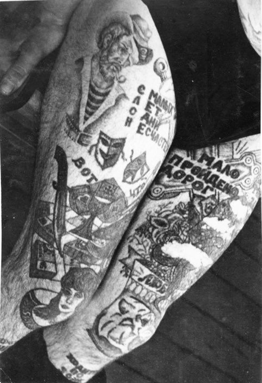 On his right leg is the acronym ‘SLON: S malih Let Odni Neschastya,’ which translates to 'Only Misfortunes from an Early Age.' Text under this reads ‘Here is what [is killing us].' The dagger, cards and money are a variation of the popular tattoo ‘These are the things that destroy us.' Text at the top of the left leg reads ‘Few roads have been walked.' Text by the knee reads ‘Love.' Text on the shin reads ‘It [the leg] walks around the zone.' The theatre masks on the right leg represent happiness (before prison) and sadness (after prison).