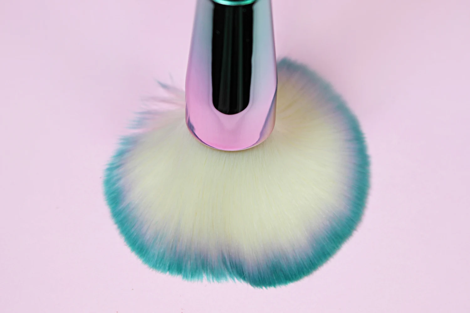 close-up of bright, iridescent makeup brushes on an eastehtic pink background