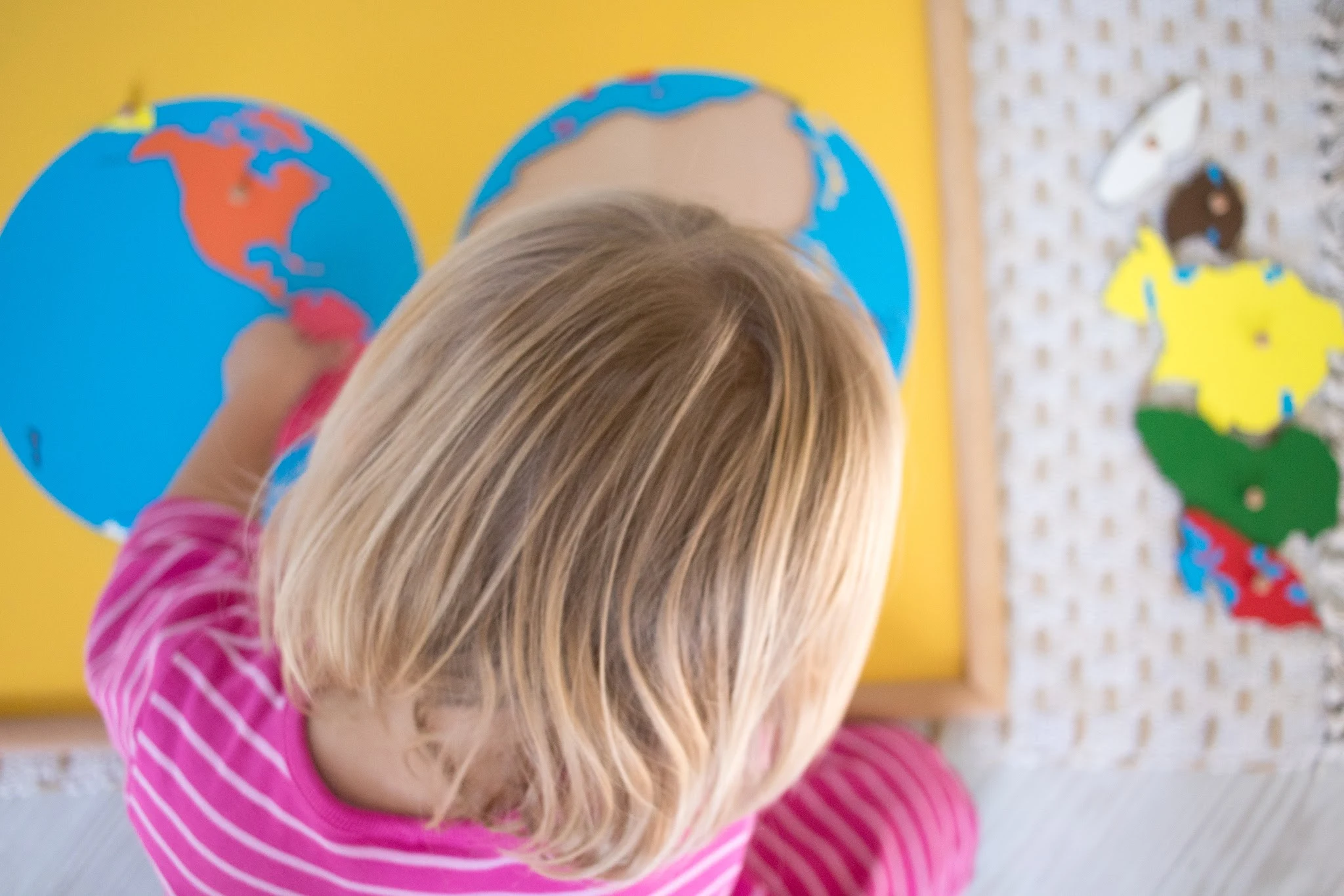 Small preschool child uses Montessori continent puzzle map in their home