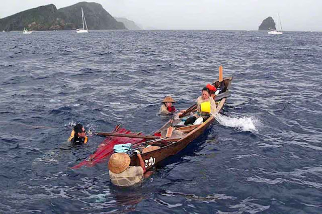 uprighted boat, bailing water, removing the sail, team in water