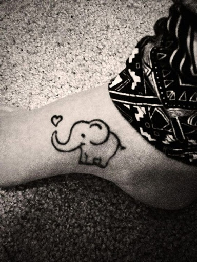 Um estilo cartoon elefante é ilustrada na utente de pé em tinta preta, com um coração no final de seu tronco esta tatuagem.