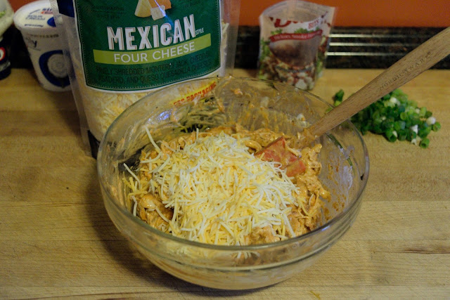 A picture of the shredded cheese being added to the bowl of chicken mixture.