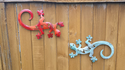 Decorative metal gecko sculptures on the fence.