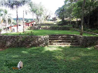 Escada de pedra no jardim com pedra rachão, um tipo de pedra rústica que é a sobra de pedra quando está tirando a pedra paralelepípedo ou a pedra rachão, com os muros de pedra em área de lazer de condomínio em Atibaia-SP.