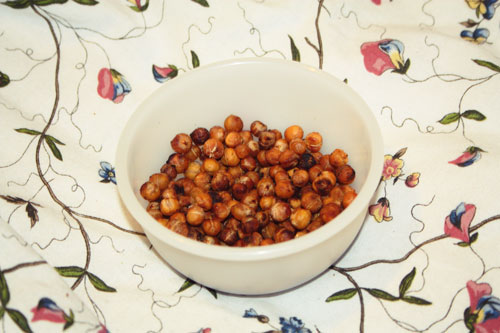 Spicy Roasted Chickpeas in a tupperware bowl, on an IKEA duvet