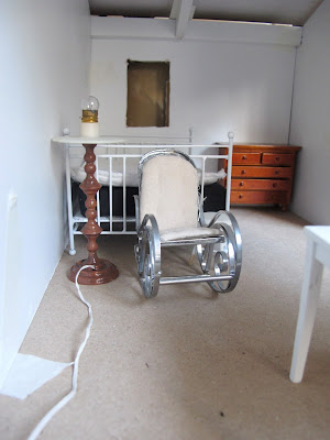 Modern dolls' house miniature floor lamp next to a rocking chair in a dry-fitted miniature kit shed.