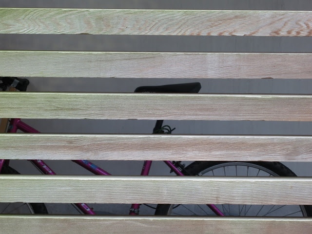 Red bike with sloping cross-bar in safe area behind new wooden planks.