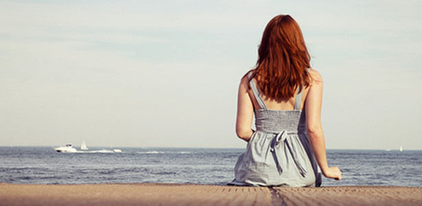 Mujer reflexionando a la orilla del mar sobre la infidelidad y el matrimonio