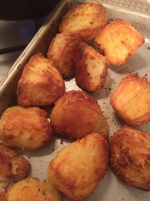 A baking tray filled with golden brown roast potatoes