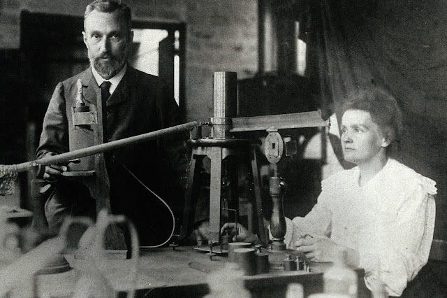 Pierre and Marie Curie in the laboratory, demonstrating the experimental apparatus used to detect the ionisation of air, and hence the radioactivity, of samples of purified ore which enabled their discovery of radium | c:a 1904 | Wikipedia Image: Pierre and Marie Curie in the laboratory, demonstrating the experimental apparatus used to detect the ionisation of air, and hence the radioactivity, of samples of purified ore which enabled their discovery of radium | c:a 1904 | Wikipedia