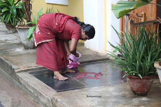 A woman drawing Kolam at the entrance