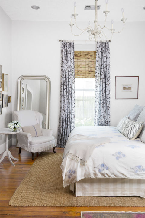 Beautiful bedroom with blue decor in a charming cottage in Texas with interior design by Holly Mathis. Blue print churtains, a natural jute rug over pine floors, and a cozy cottage style arm chair star in the winning mix. #bedroom #decorating #bluebedroom #farmhouse #cottage