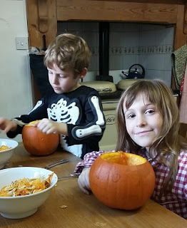 Picture of my two children carving Halloween pumpkins at the kitchen table