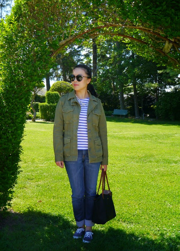 Casual travel style with an army jacket, Breton stripes, jeans, and statement shades and necklace