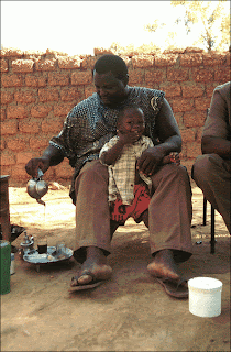 In Sevare, a town in the Mopti Region of Mali a man is involved in the elaborate tea ceremony as his young son looks on.