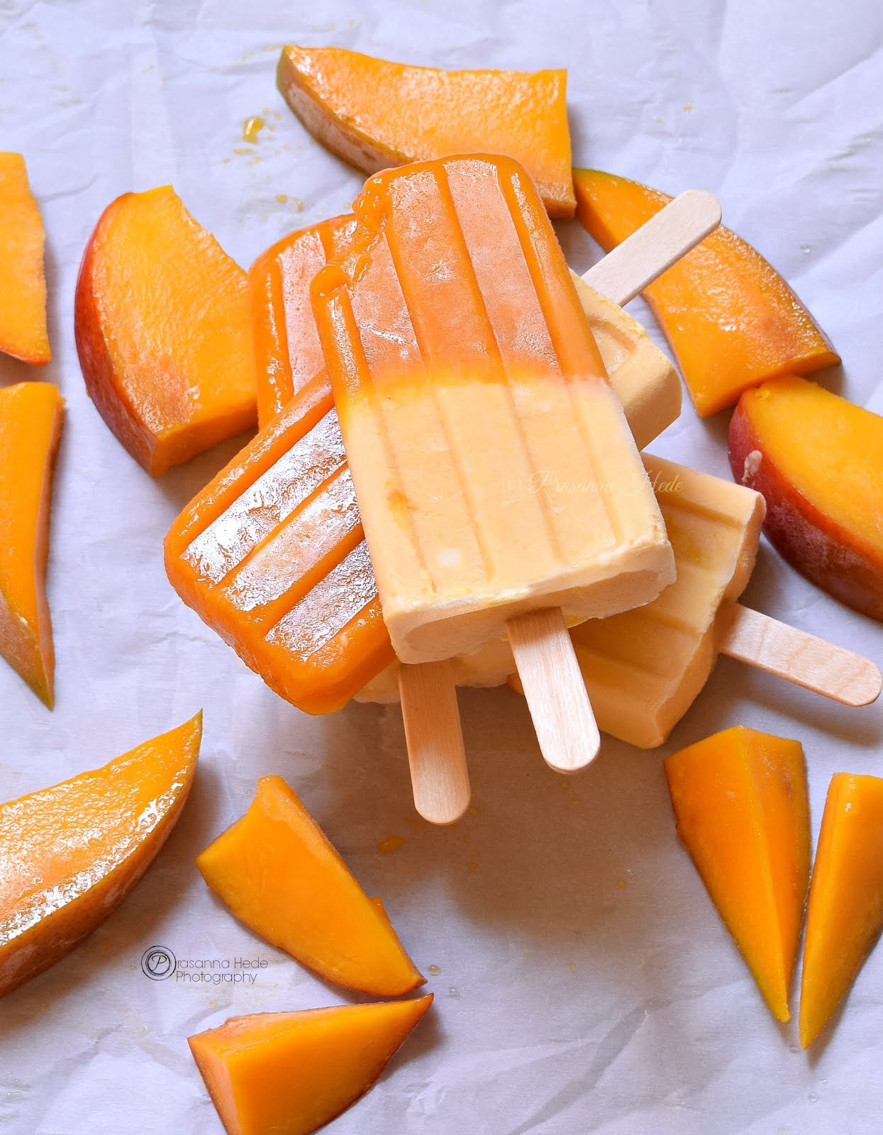 Anotger look of Mango Creamy Popsicles spread along with cut Mango pieces