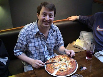 The Twitter picture that started it all. Features David Mitchell smiling gleefully with a pizza in front of him.