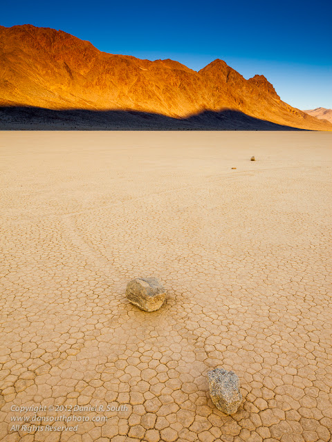a photograph of sliding rocks on the racetrack playa in death valley at sunrise