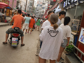 "Smile" with a smile below on the back of shirt worn by a young woman
