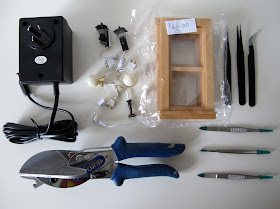 Various tools and items for miniature making including windows and lights, a transformer, tweezers and an Ezy Cutter.