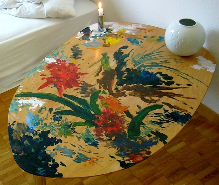 Bemalter Tisch mit brennender Kerze und runder, weisser Vase