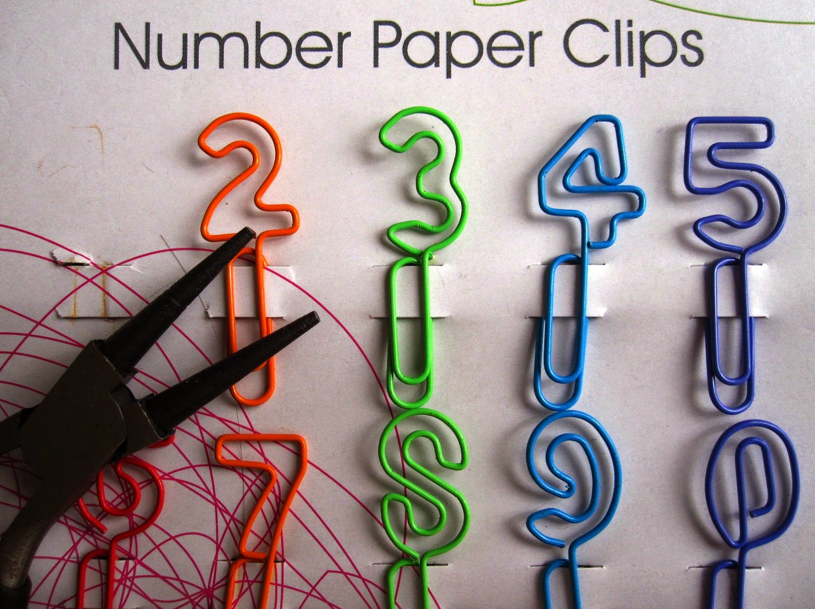 Packet of colourful wire number paperclips with a pair of pliers.