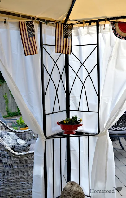 corner of a gazebo with white curtains and flags