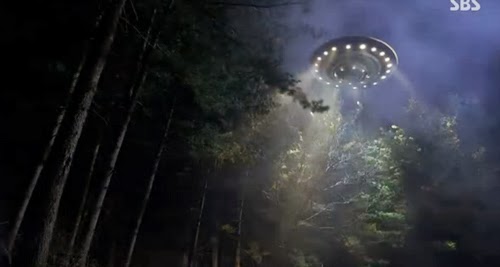 A UFO flies above the trees.