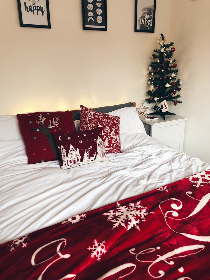 bedroom with christmassy pillows and a christmas tree