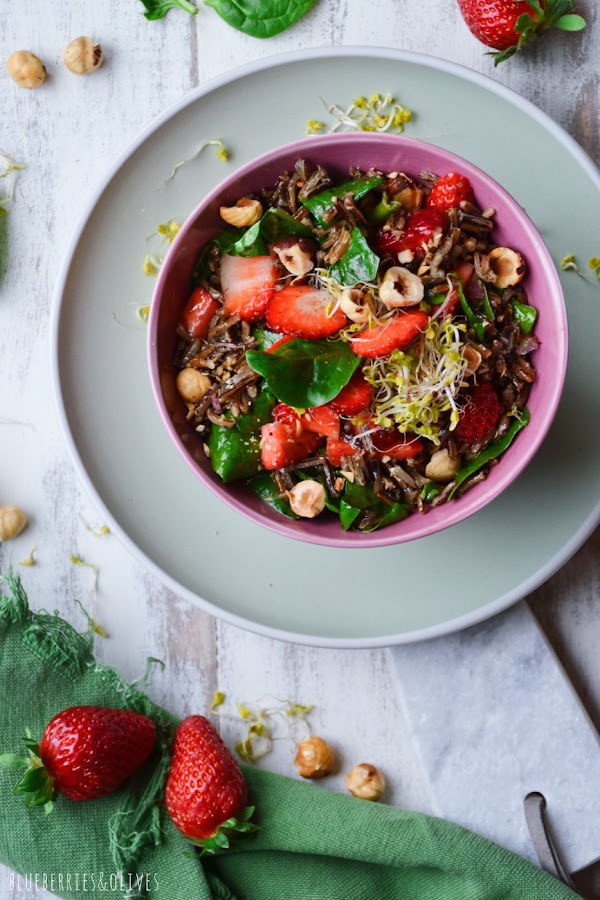 PLANO CENITAL ENSALADA DE ARROZ SALVAJE EN BOL ROSA, PLATO VERDE, FONDO BLANCO Y TRAPO VERDE, HOJAS DE ESPINACA Y FRESAS