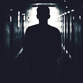 Man walking down a dark corridor towards the light, addiction and darkness