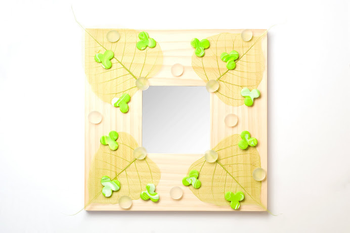 Specchio con foglie, sassi e formine in fimo
