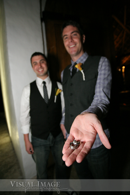Groom holding wedding rings while standing next to best man