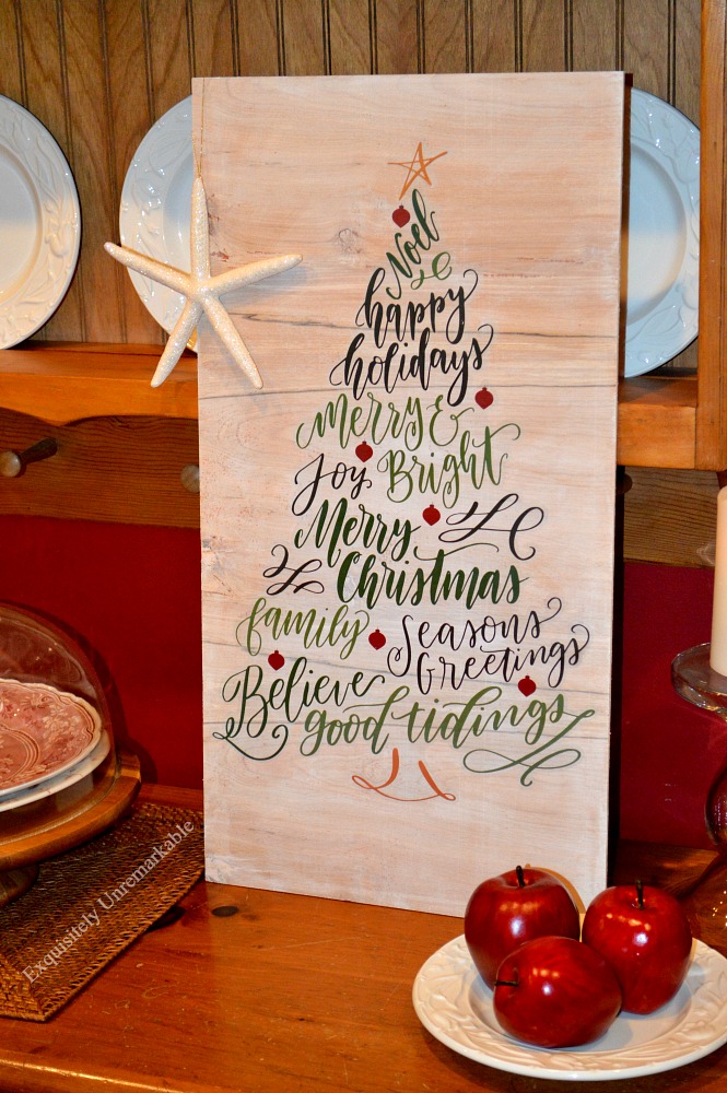 Whimsical Christmas Tree Sign with a starfish hanging off it and displayed on a buffet