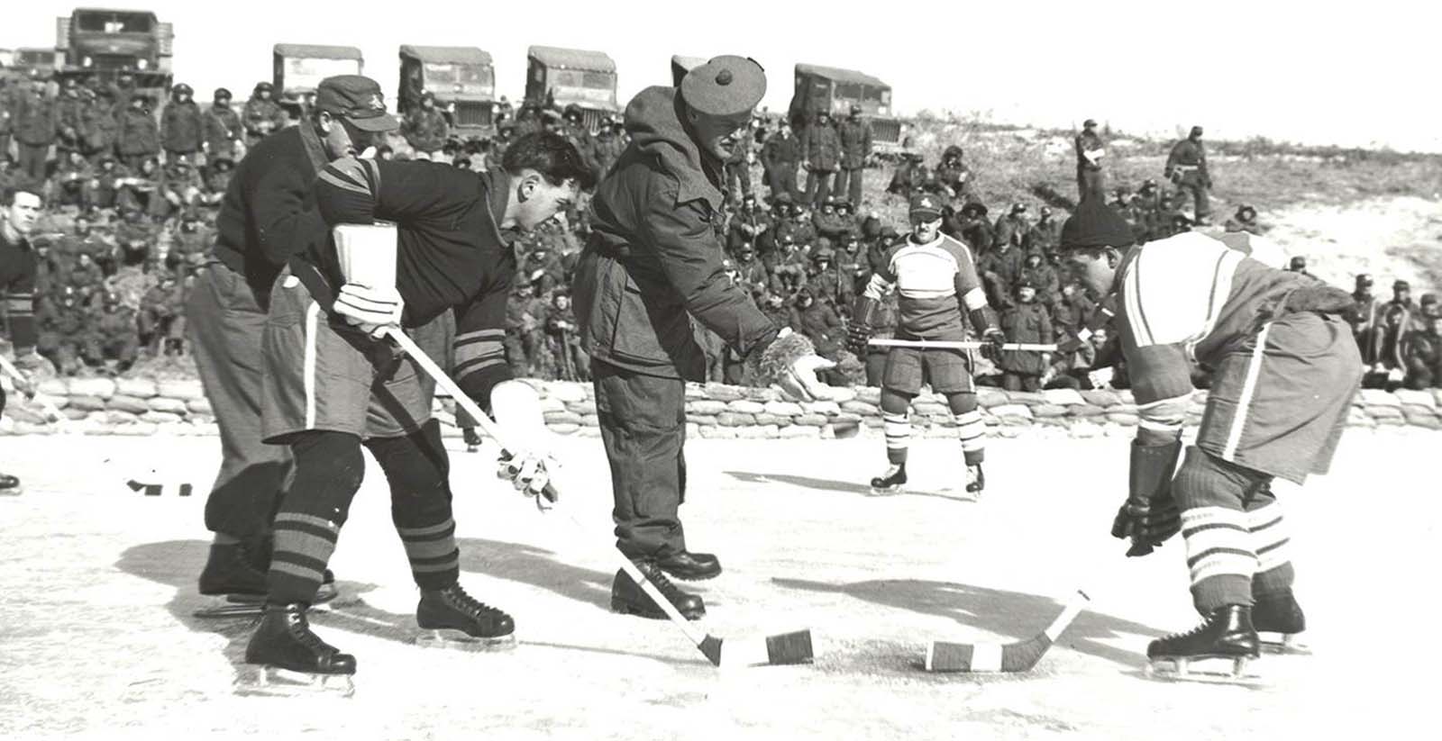 Brigadier John Rockingham drops the puck for a match between 1st Battalion, Princess Patricia’s Canadian Light Infantry (left) and 2nd Battalion, Royal 22e Regiment “Vandoos” (right) during the Korean War. Playing for the Patricias was Private W. Wolfe. For the Royal 22e Regiment, Private R. Halley. 
