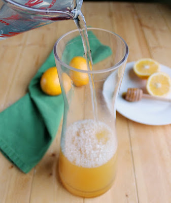 Refreshing and naturally sweetened lemonade is just a few minutes away. This simple drink recipe is a perfect summertime cooler. pouring water into Grosche pitcher that already has lemon juice and honey in it