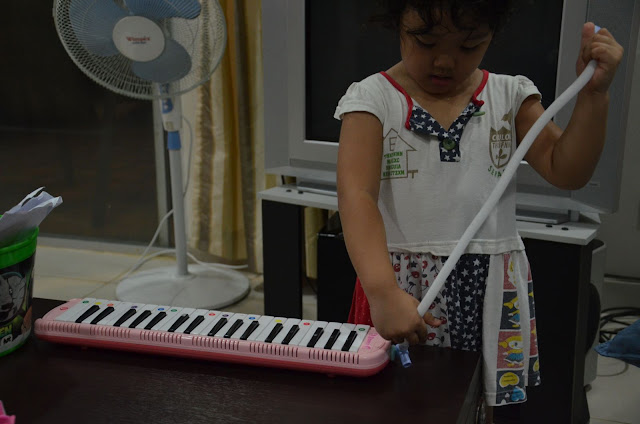 Kecil playing the pianika indoor