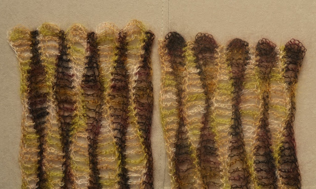 Close up of scarf ends. The widest parts of the stripe end in a curved scallop shape and the thinnest parts end with a single stitch.