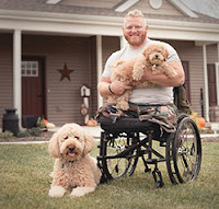 Wounded vet in wheelchair in front of his house.