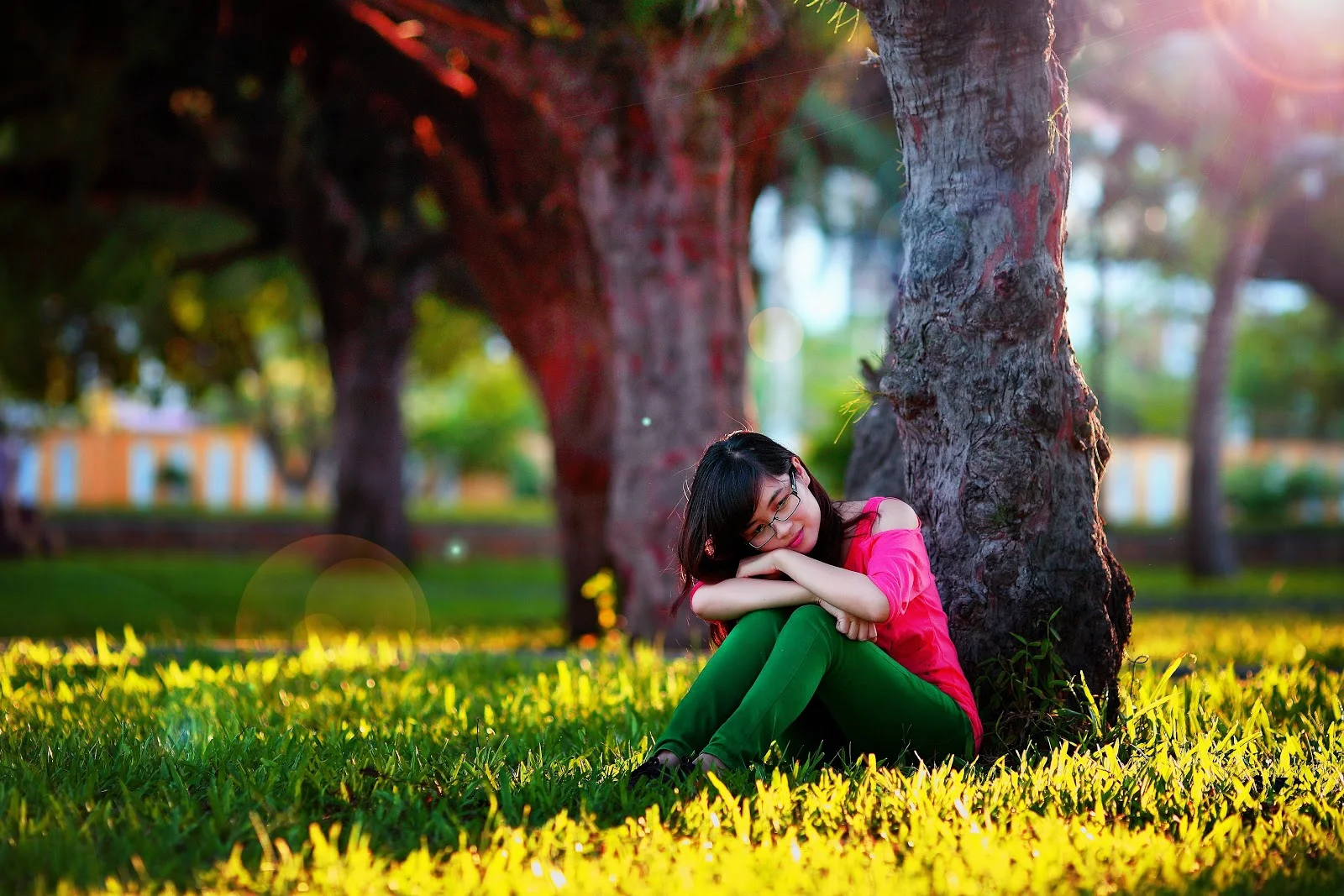 草地に座って温和な表情を浮かべながら考える女性