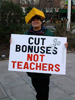 man with Wisconsin cheesehead hat and sign that said cut bonuses not teachers