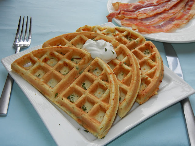 waffles on a plate with a dollop of sour cream and a fork to the left 