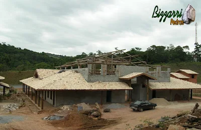 Fachada dos fundos da construção rústica na parte da execução do madeiramento com eucalipto tratado em fase final já iniciando a execução da cobertura do telhado com telhas de barro colonial mesclada.