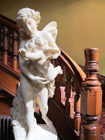 Large statue at the foot of a curved staircase.